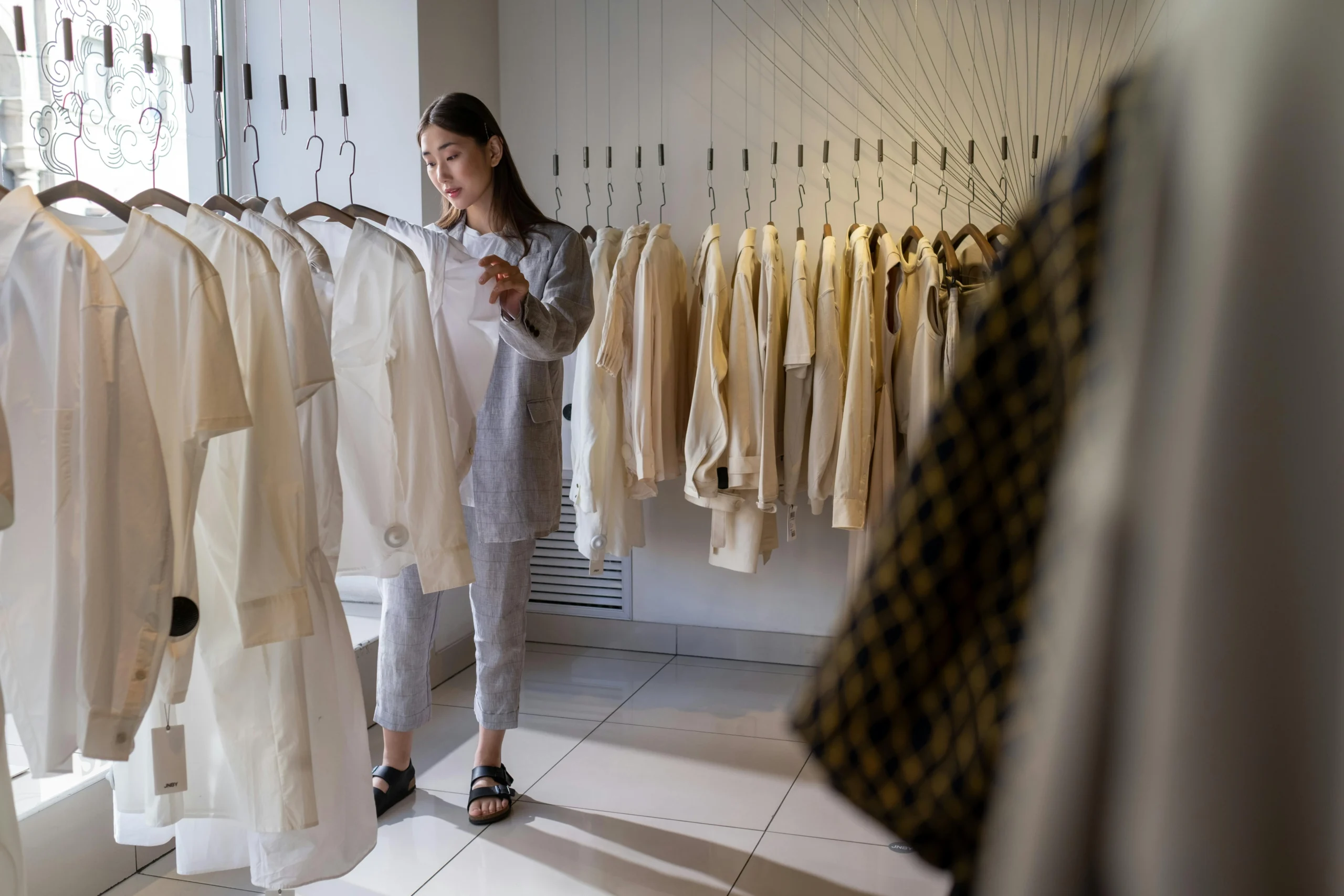The Benefits of Minimalism for Mental Health and Well-Bein Woman choosing neutral clothing in a minimalist wardrobe setting